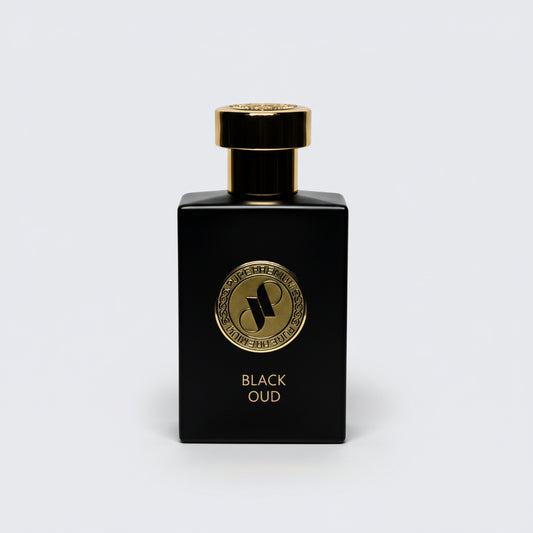 Black perfume bottle with gold cap and label on a light gray background